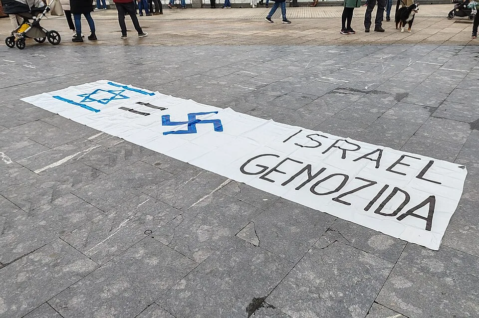 Protest banner reading Israel Genozida with an Israeli flag and swastika